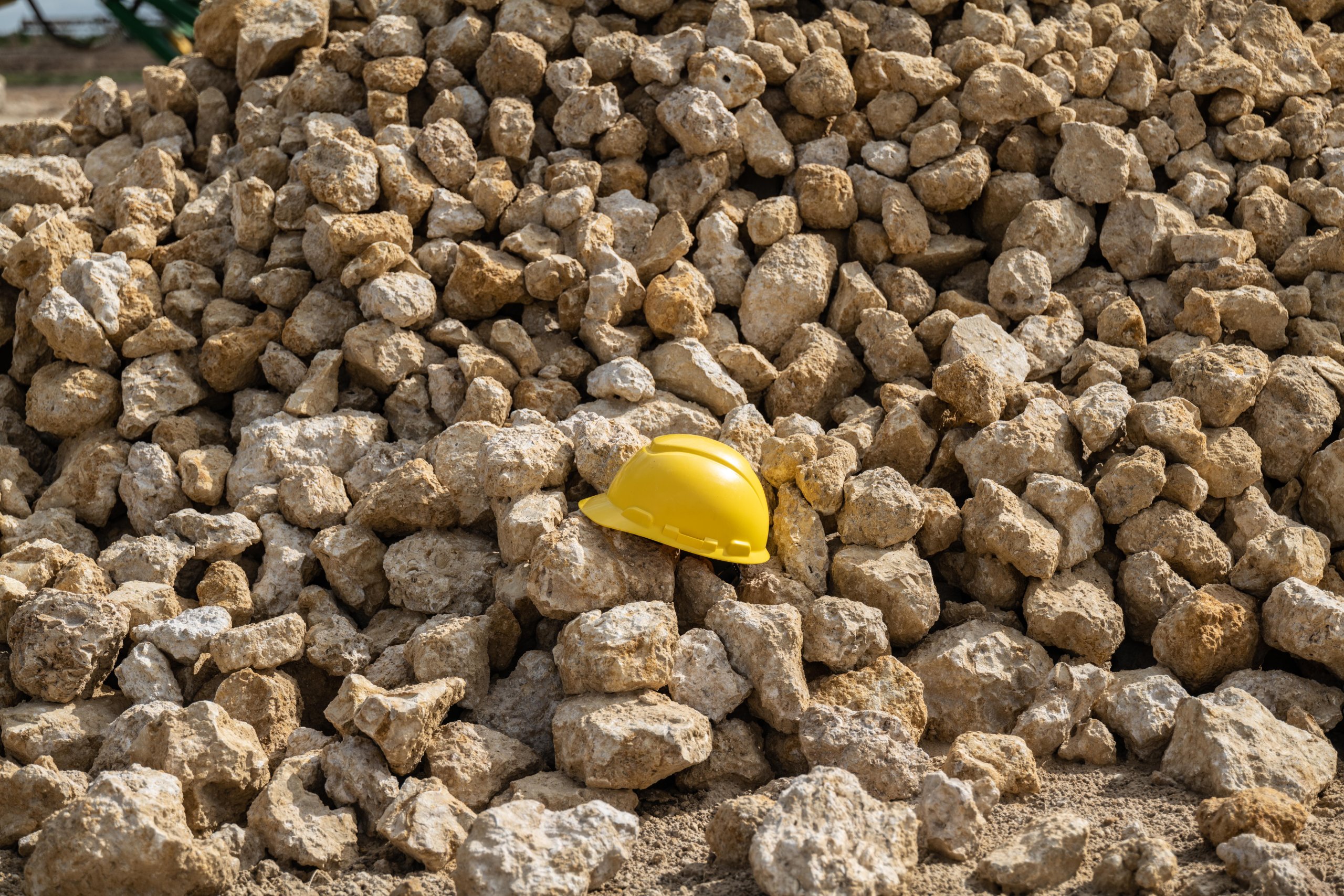 
Yellow hard hat resting on a large stockpile of crushed limerock aggregate at Delta Aggregate's facility in Immokalee, Florida