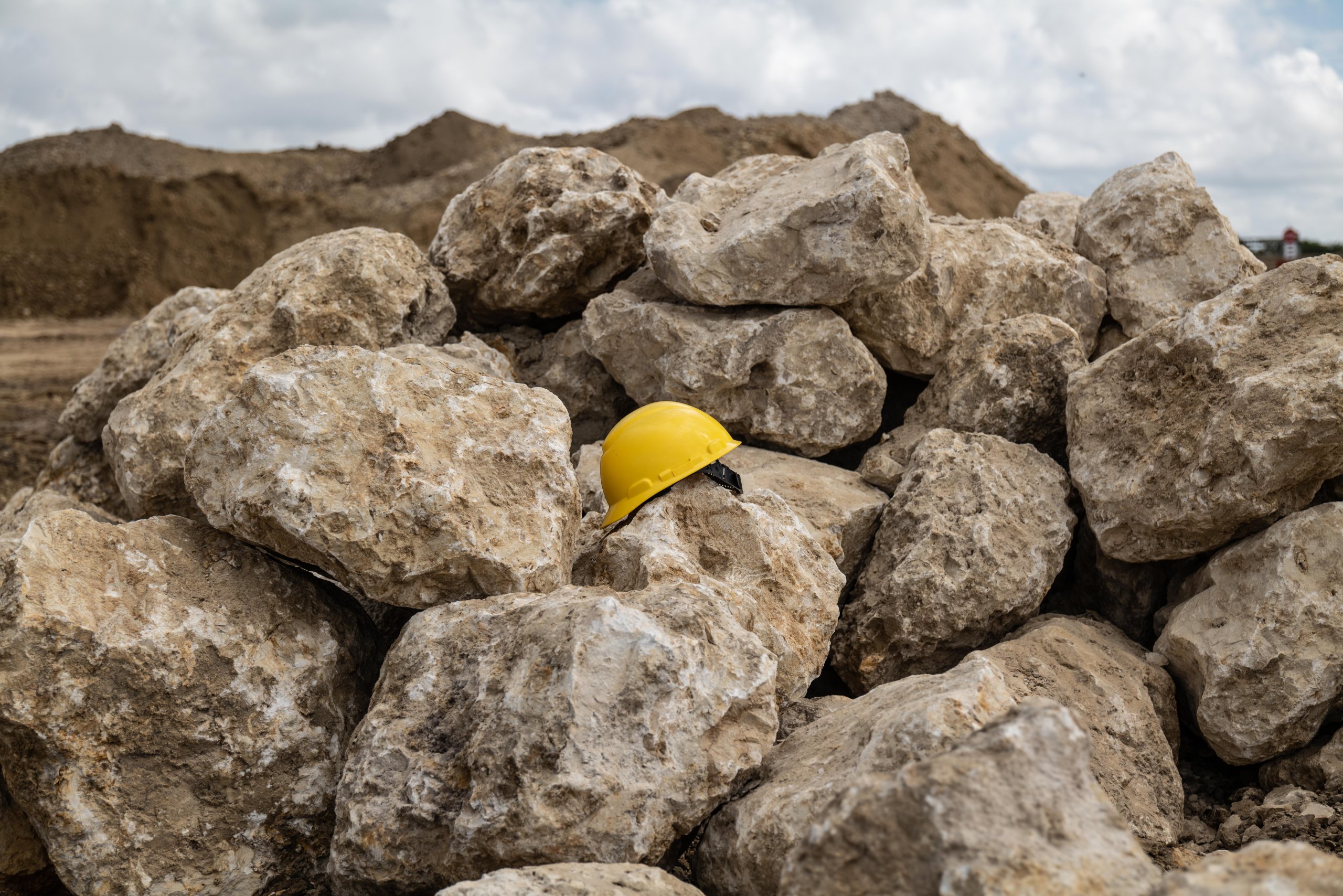 Large limerock boulders stockpiled at Delta Aggregate's Immokalee, Florida facility with a yellow hard hat placed among the stones for scale